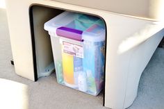 a plastic container with various containers in it sitting on the floor next to a couch