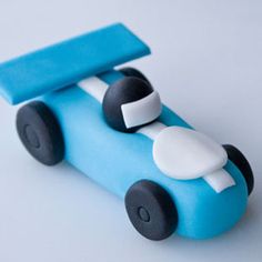 a cake shaped like a toy car on a white table with blue and black trim