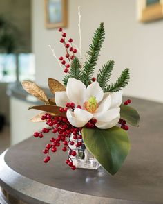 a vase filled with flowers and greenery on top of a table