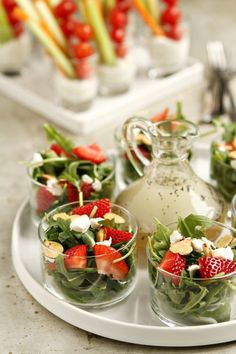 salads and fruit are arranged on a tray