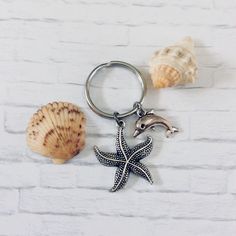 three seashells and a starfish on a white brick wall with one keychain