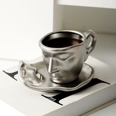 a silver cup and saucer sitting on top of a book