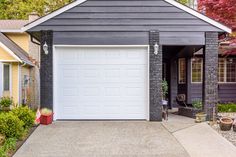 a house with a white garage door in the front yard and landscaping around it on a sunny day