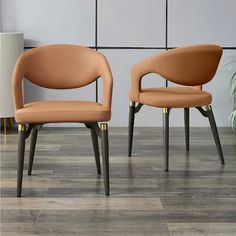 two brown chairs sitting next to each other on top of a hard wood floor in front of a wall