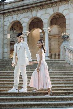 a man and woman standing on steps holding hands