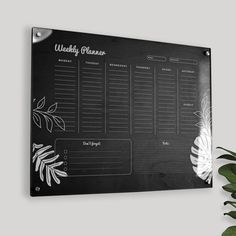 a black and white wedding planner on a wall next to a potted plant with leaves