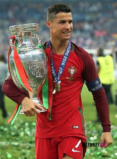 a soccer player holding a trophy on top of a field