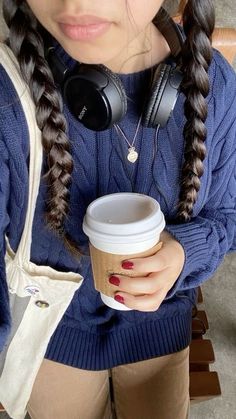 a woman with headphones holding a cup of coffee