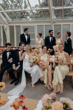 a group of people sitting around each other at a table with flowers in front of them