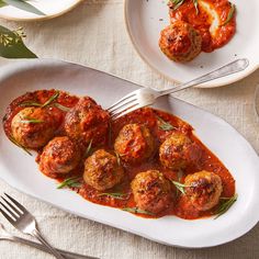 meatballs covered in tomato sauce and garnished with herbs on a white plate