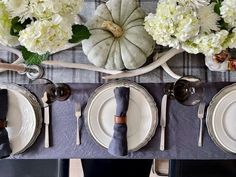 the table is set with plates, silverware and pumpkins on it's head