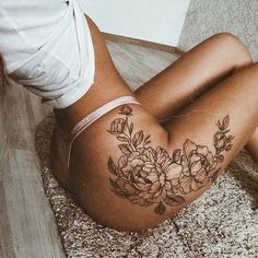 a woman laying on the floor with her stomach covered in flowers and leaves tattoo design