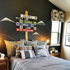 a bed room with a neatly made bed and lots of signs on the wall above it