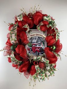 a christmas wreath hanging on the wall with red bows and green ornaments around it's edges