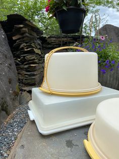 two white cakes sitting next to each other on top of a stone slab with flowers in the background