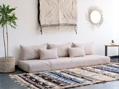 a living room with a couch and rugs on the floor next to a potted plant