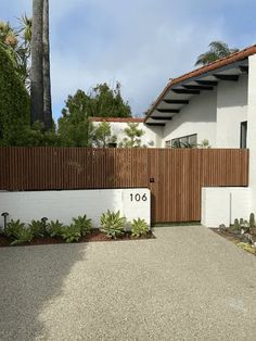 a white house with a wooden fence and number on the front door is seen in this image