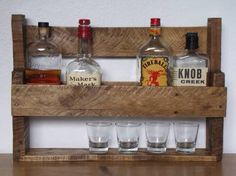 an old wooden shelf with liquor bottles and shot glasses on it's bottom rack