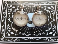 two earrings with words on them are sitting on a table next to a black and white background