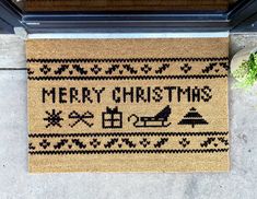 a merry christmas door mat on the ground next to a potted plant and window