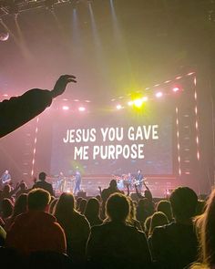 a man standing on top of a stage holding his hand up in front of an audience