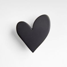 a black heart shaped pin sitting on top of a white surface