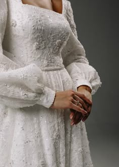 a woman in a white dress is holding her hands together