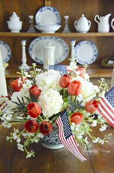 a vase filled with red, white and blue flowers on top of a wooden table