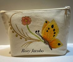 a white pouch with a yellow butterfly on it and the words rosy jacoo written in black