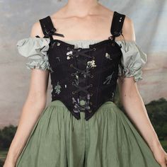 As soft and strong as she is striking, the Black Wildflower Renaissance Corset makes a boldly beautiful first impression. Pair with midnight blue, violet, and black for an enhanced dramatic effect, or soften the look by bringing out the lavender and emerald accents in the embroidered wildflower detail. Ribbon ties add a chic embellishment to the collarbone, making this corset as easy to dress up for a formal affair as it is to slip over a linen chemise for a daytime Renaissance Faire look. Suppo Corset Outfit Skirt, French Meadows, Linen Chemise, Cottagecore Corset, Floral Corset, Witch Costume, Lace Bustier, Blue Violet, Clothing Hacks