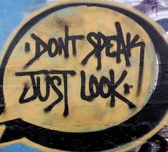 black and white graffiti on the side of a wall that says don't speak just look