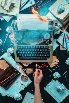 an old fashioned typewriter surrounded by many different types of paper and pencils on a table