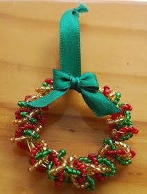 a green ribbon is attached to a beaded christmas wreath ornament on a wooden table