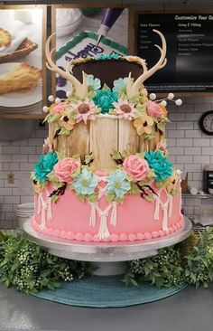 a cake decorated with flowers and deer antlers on top of a table in a bakery