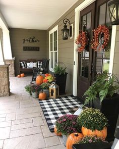 the front porch is decorated with pumpkins and flowers