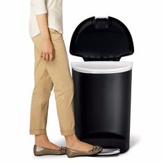 a woman standing next to a trash can