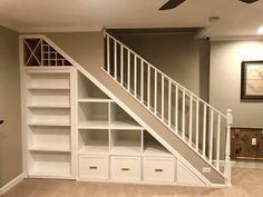 an empty living room with white bookcases and stairs