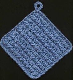 a blue crocheted square with a button on the end is sitting in front of a black background