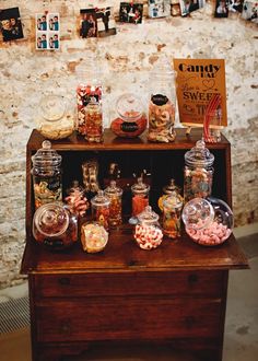 an old wooden cabinet filled with candy and candies next to a wall covered in pictures