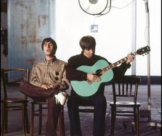 two young men sitting on chairs playing guitars