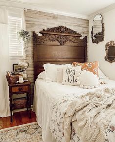 a bed with white linens and pillows in a bedroom next to a wooden headboard