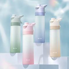 four different colored water bottles on display in front of a blue sky and white background