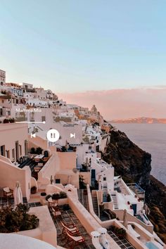 an aerial view of white buildings on the cliff overlooking the ocean at sunset or sunrise