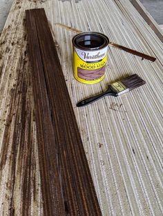 a paint can sitting on top of a wooden table next to a brush