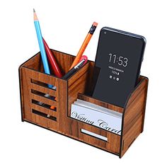 a cell phone and pencils are in a wooden holder with two compartments for pens