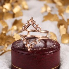 an open ring sitting on top of a wooden box next to some gold leaf decorations