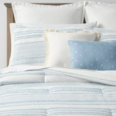 a bed with blue and white striped comforter, pillows and pillow cases on it