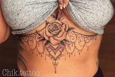 a woman's stomach with a rose tattoo on the side and an intricate design