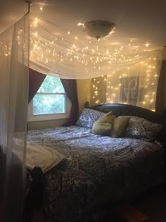 a bed that has some lights on the headboard and canopy over it, in front of a window