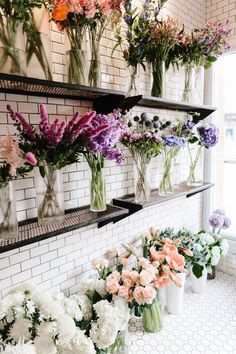 several vases filled with different types of flowers sitting on shelves next to each other